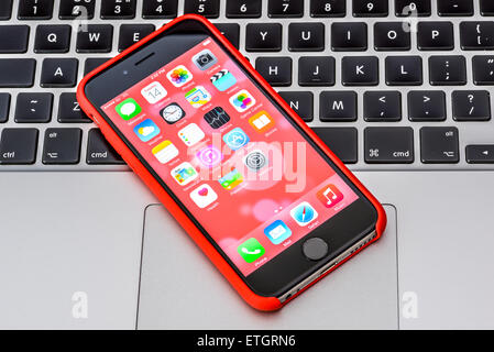 iPhone 6 in red case on an Apple Macbook keyboard Stock Photo