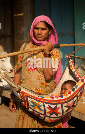 Rajasthani woman carrying her baby in a sling. Jaisalmer, Rajasthan, India Stock Photo