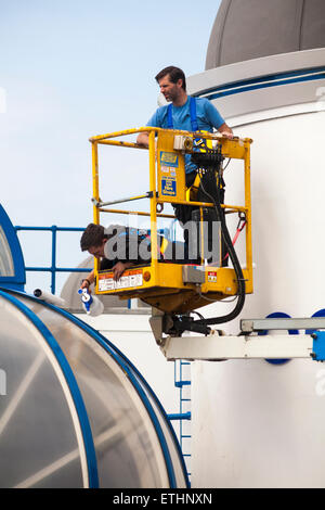 Two men working in cherrypicker cleaning the panels on the roof of the Aquarium, Bournemouth in June Stock Photo