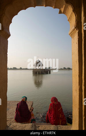 Indian women in saris feeding catfish at Gadi Sagar, Gadisar lake, Jaisalmer, Rajasthan, India Stock Photo