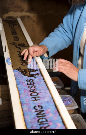 UK, England, Derbyshire, Eyam, hands of volunteer constructing the Requisitioning of Horses 2014 well dressing Stock Photo