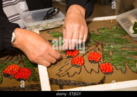 UK, England, Derbyshire, Eyam, hands of volunteer constructing the Requisitioning of Horses 2014 well dressing Stock Photo