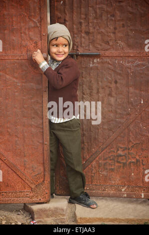 Indian boy with hole in shoe at doorway. Jodhpur, Rajasthan, India Stock Photo