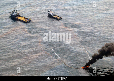 Clean up crews conduct controlled burns of oil gathered from the surface of the Gulf of Mexico following the BP Deepwater Horizon oil spill disaster as efforts to contain and clean the millions of gallons of crew continue May 6, 2010 in the Gulf of Mexico. Stock Photo