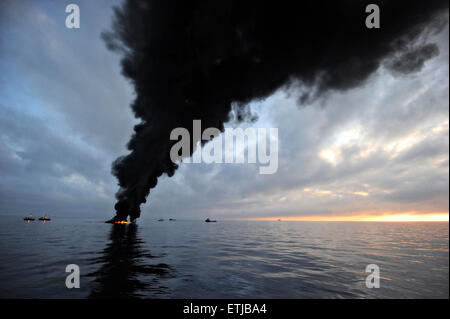 Dark clouds fill the sky as clean up crews conduct controlled burns of oil gathered from the surface of the Gulf of Mexico following the BP Deepwater Horizon oil spill disaster as efforts to contain and clean the millions of gallons of crew continue May 7, 2010 in the Gulf of Mexico. Stock Photo