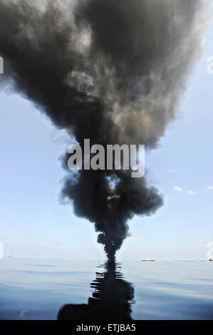 Dark clouds fill the sky as clean up crews conduct controlled burns of oil gathered from the surface of the Gulf of Mexico following the BP Deepwater Horizon oil spill disaster as efforts to contain and clean the millions of gallons of crew continue May 6, 2010 in the Gulf of Mexico. Stock Photo