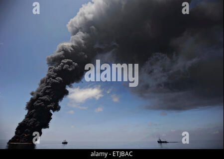 Dark clouds fill the sky as clean up crews conduct controlled burns of oil gathered from the surface of the Gulf of Mexico following the BP Deepwater Horizon oil spill disaster as efforts to contain and clean the millions of gallons of crew continue May 6, 2010 in the Gulf of Mexico. Stock Photo