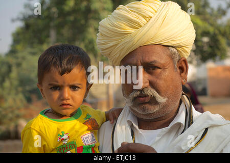 Rajasthani man in white with distinctive turban and child. Rural village near Jodhpur, Rajasthan, India. Stock Photo