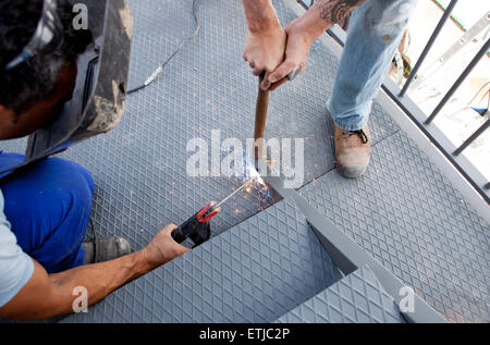 Two men working over iron platform with arc welding Stock Photo
