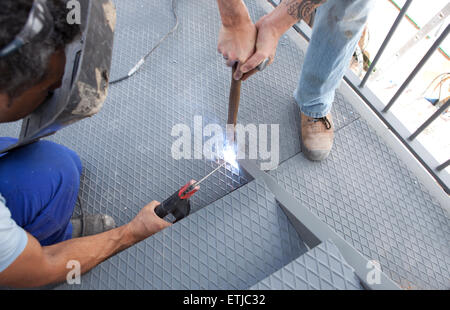 Two men working over iron platform with arc welding Stock Photo