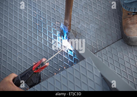 Two men working over iron platform with arc welding Stock Photo