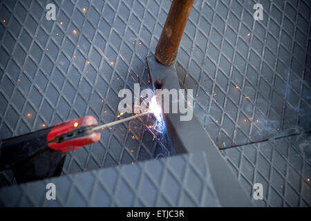 Two men working over iron platform with arc welding Stock Photo