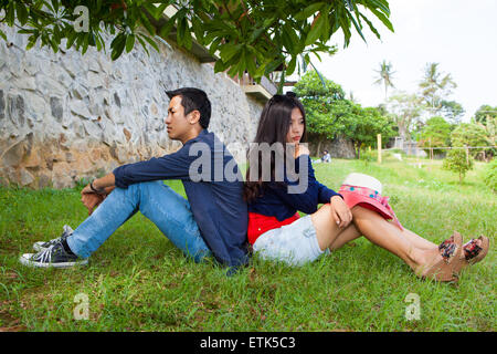 Asian couple mad at each other on green grass outdoor Stock Photo