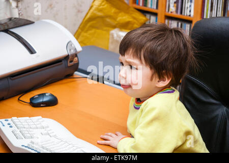 3 to 5 year old Caucasian boy, indoor. Sitting at computer looking very puzzled impressed on his face. Overhead view Stock Photo