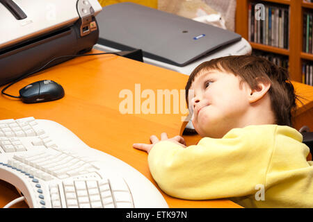 3 to 5 year old Caucasian boy, indoor. Sitting at computer looking very puzzled impressed on his face. Overhead view Stock Photo