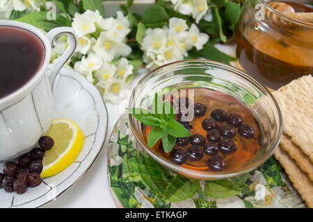 Chokeberry tea in a porcelain cup on a flower decorated table Stock Photo