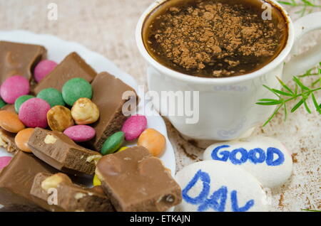 Chocolate coffee with bonbons and a 'good day' message written on pebbles Stock Photo