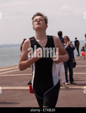 Portsmouth, UK. 14th June, 2015. A young athlete taking part in the the under 16 triathlon approaches the finish line of the Portsmouth Try a tri triathlon. The event consisted of a number of sprint triathlons of different lengths to accomodate differing abilities. Credit:  simon evans/Alamy Live News Stock Photo