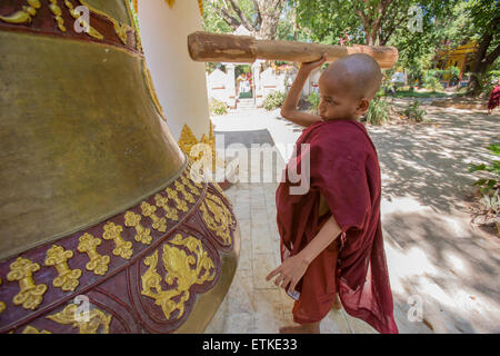 Novice monk ringing bell at Kalaywa Tawya monastery in Yangon Myanmar Stock Photo