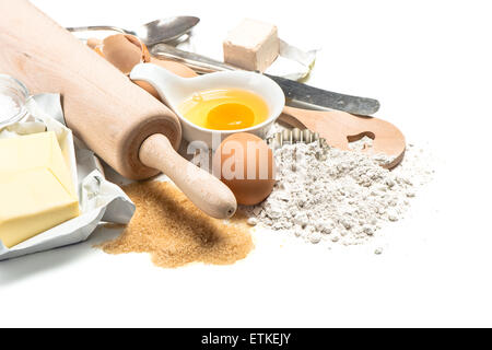 Baking ingredients flour, eggs, yeast, sugar, butter. Wooden kitchen utensils rolling pin and spatula. Food background Stock Photo