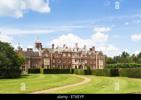 View of Sandringham House, a country house, the Norfolk retreat of the Queen in East Anglia, in summer with a blue sky and fluffy white clouds