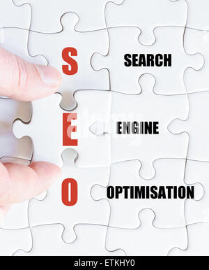 Hand of a business man completing the puzzle with the last missing piece.Concept image of Business Acronym SEO as Search Engine Optimisation Stock Photo