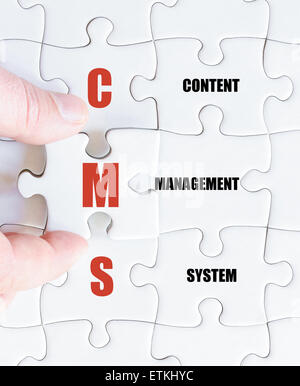 Hand of a business man completing the puzzle with the last missing piece.Concept image of Business Acronym CMS as Content Management System Stock Photo