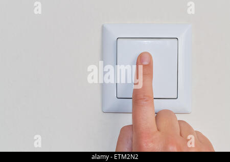 A hand of a woman pressing a wall mounted light switch Stock Photo
