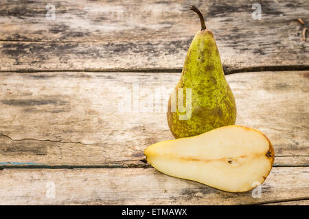 Full and cut in half pear fruit on wooden background with copy space. Stock Photo