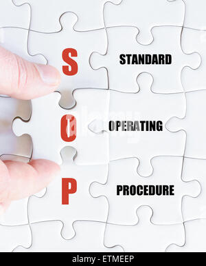 Hand of a business man completing the puzzle with the last missing piece.Concept image of Business Acronym SOP as Standard Operating Procedure Stock Photo