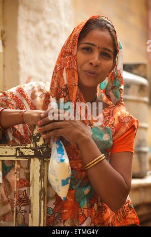 Indian woman in bright sari carrying sachet of milk.  Jaisalmer, Rajasthan, India Stock Photo