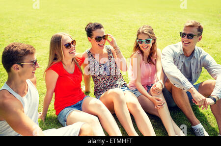 group of smiling friends outdoors sitting in park Stock Photo