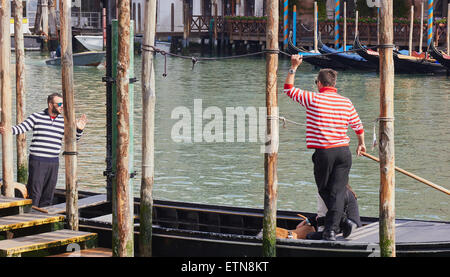 Two gondoliers in striped tops preparing to row a traghetto cross the Grand Canal Venice Veneto Italy Europe Stock Photo