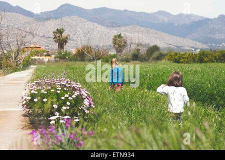 Rear view of two girls walking in a field Stock Photo