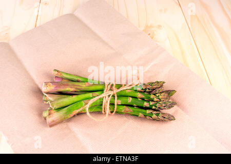 Bunch of fresh uncooked asparagus on wrapping paper with copy space Stock Photo