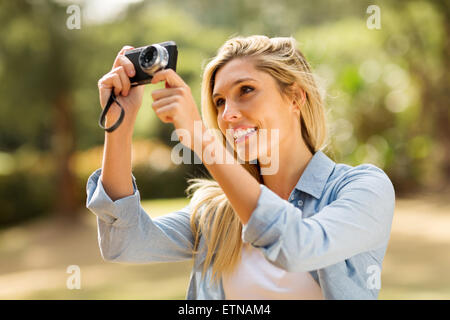 pretty blonde woman taking picture with camera outdoors Stock Photo