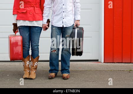 Low section of couple holding a suitcase and guitar case Stock Photo