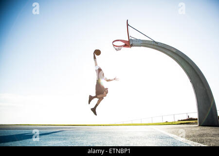 Young man playing basketball in a park, Los Angeles, California, USA