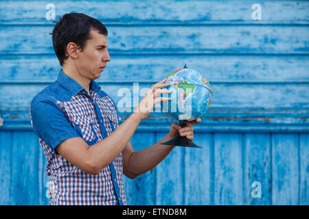 The man in the street holding a globe on a blue background summe Stock Photo