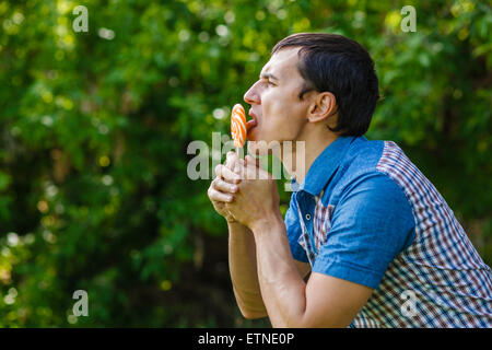 The man in the street holding a lollipop on a green background Stock Photo
