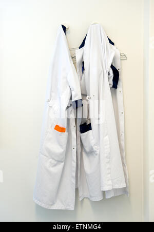 Two doctors coats hanging on a hook on the wall in a doctors room in a hospital Stock Photo