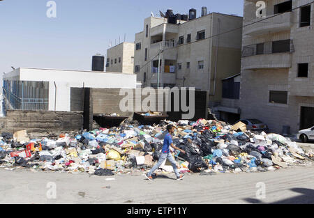 Jerusalem, Jerusalem, Palestinian Territory. 14th June, 2015. A Palestinian boy walks past piles of accumulated rubbish in the Palestinian refugee camp of Shuafat in east Jerusalem, on June 14, 2015. The refugee camp is swamped with waste because both UNWRA (United Nations Relief and Works Agency for Palestine Refugees in the Near East) and the municipality of Jerusalem, which are responsible for sanitation, haven t collect waste for almost one month © Saeb Awad/APA Images/ZUMA Wire/Alamy Live News Stock Photo