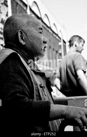 black and white Asian man  looking of into the distance from a bench at freshney place in Grimsby Stock Photo