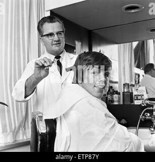 Peter Noone, lead singer of British pop group Herman Hermits, pictured visiting Mike Skotny's  barber shop straight after his arrival at Manchester airport following a world tour. 2nd March 1966. Stock Photo