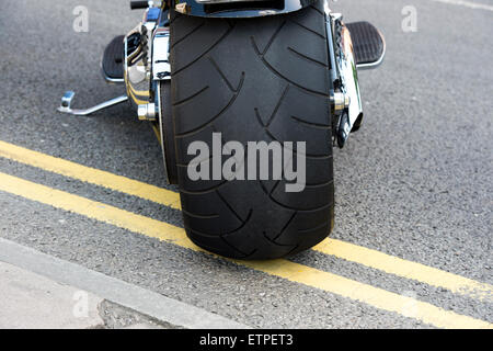 Fat back tyre on a Harley Davidson motorcycle parked on double yellow lines Stock Photo