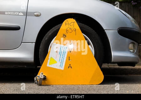 A wheel clamp fitted by the DVLA to a car whose keeper has not paid vehicle tax / has valid TAX disc. UK. Stock Photo
