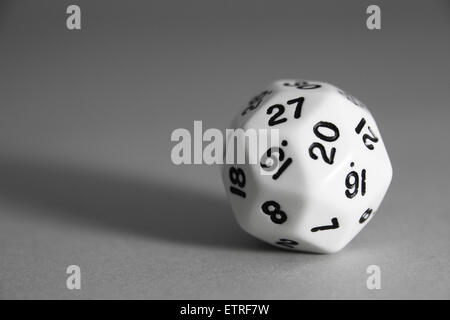 A black and white rhombic triacontahedron die on a grey background. Stock Photo
