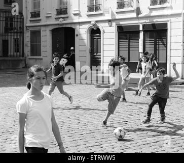 Children boys playing football on cobbled street in Lyon France Europe Stock Photo