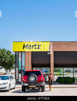 The exterior storefront of a Hertz automobile rental store with a customer in front. Oklahoma City, Oklahoma, USA. Stock Photo
