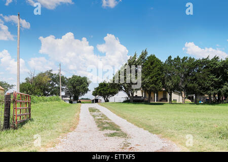 A long gravel driveway leading to a farm house and outbuildings in rural Oklahoma, USA. Stock Photo